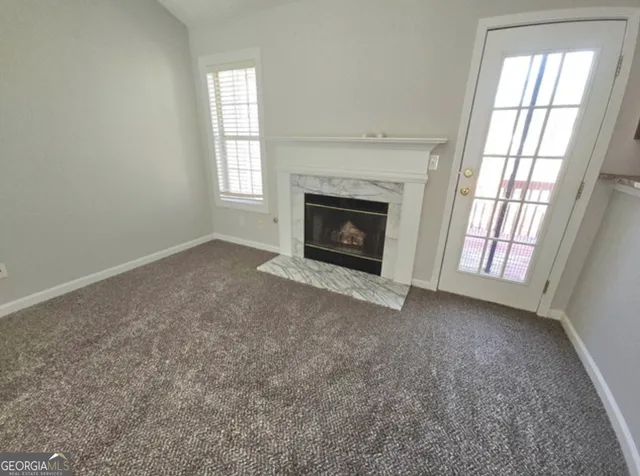 an empty room with windows and fireplace