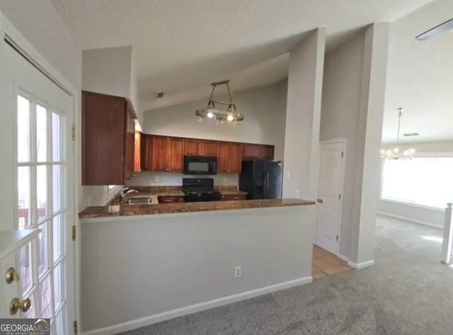 a kitchen with kitchen island granite countertop a sink and a refrigerator