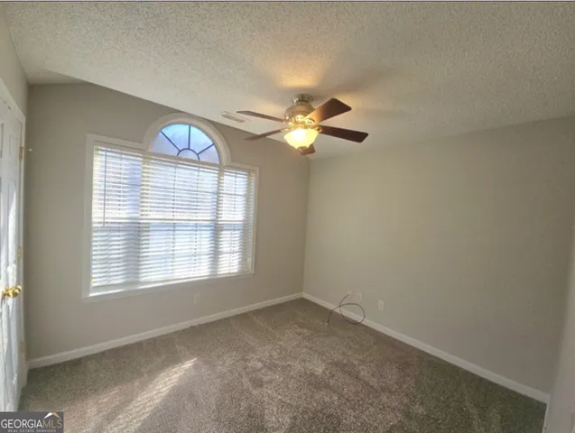 an empty room with windows and fan