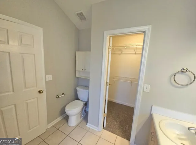 a bathroom with a granite countertop toilet and a sink