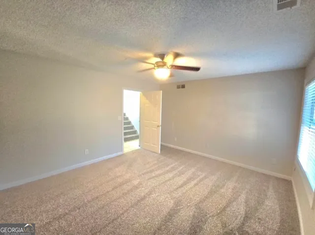 an empty room with a chandelier fan and windows