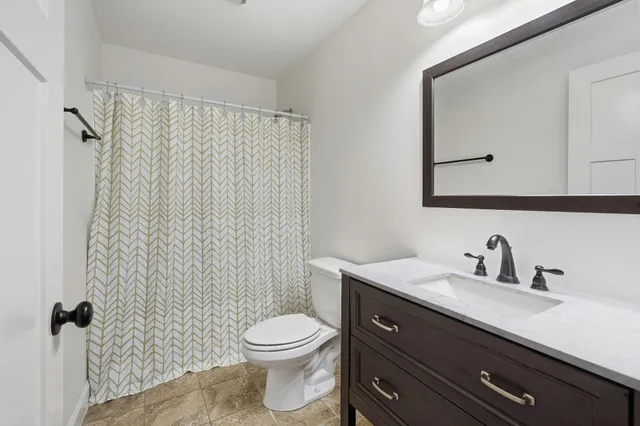 a bathroom with a toilet a sink a mirror a shower and vanity