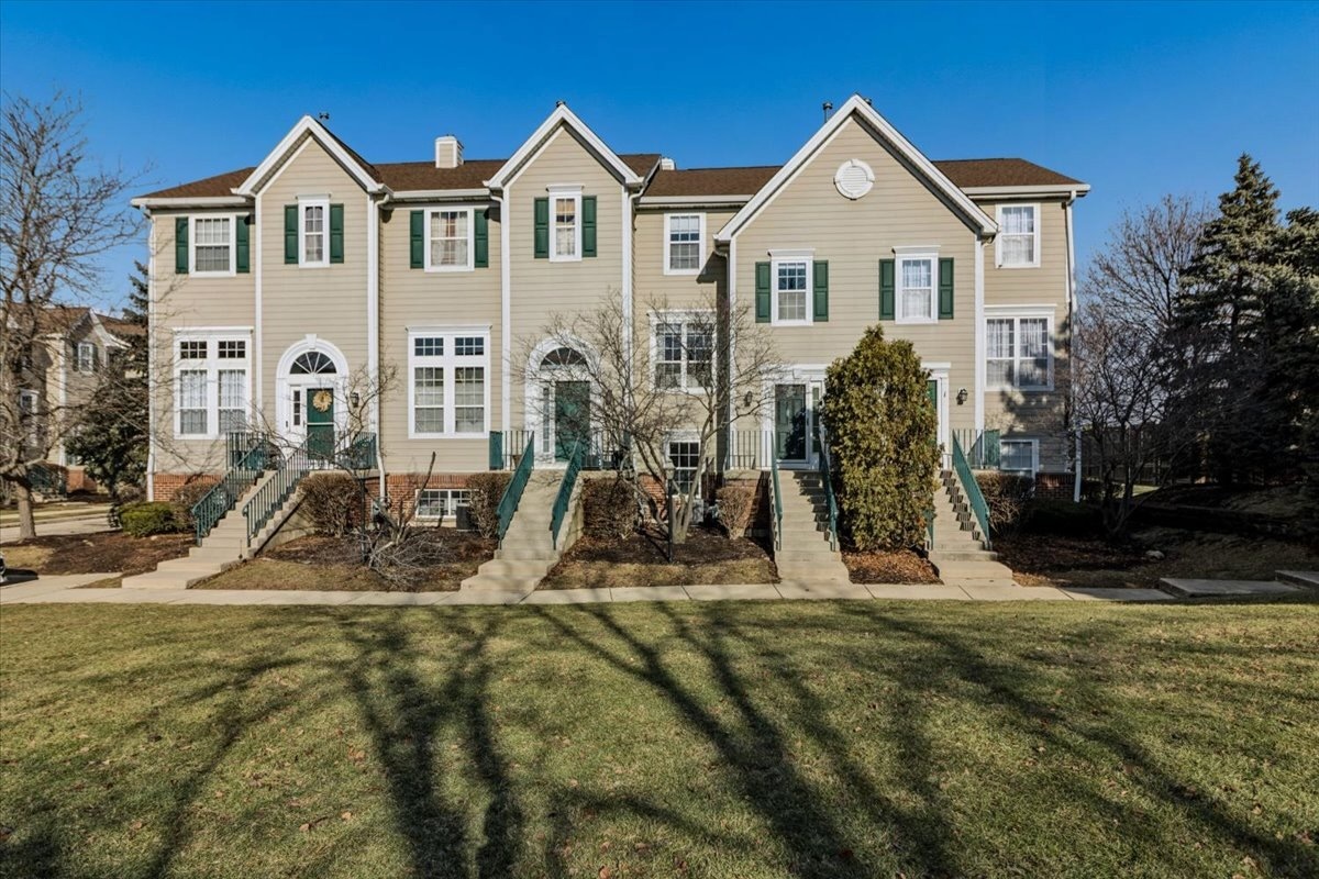 a view of a white house with a small yard and large tree