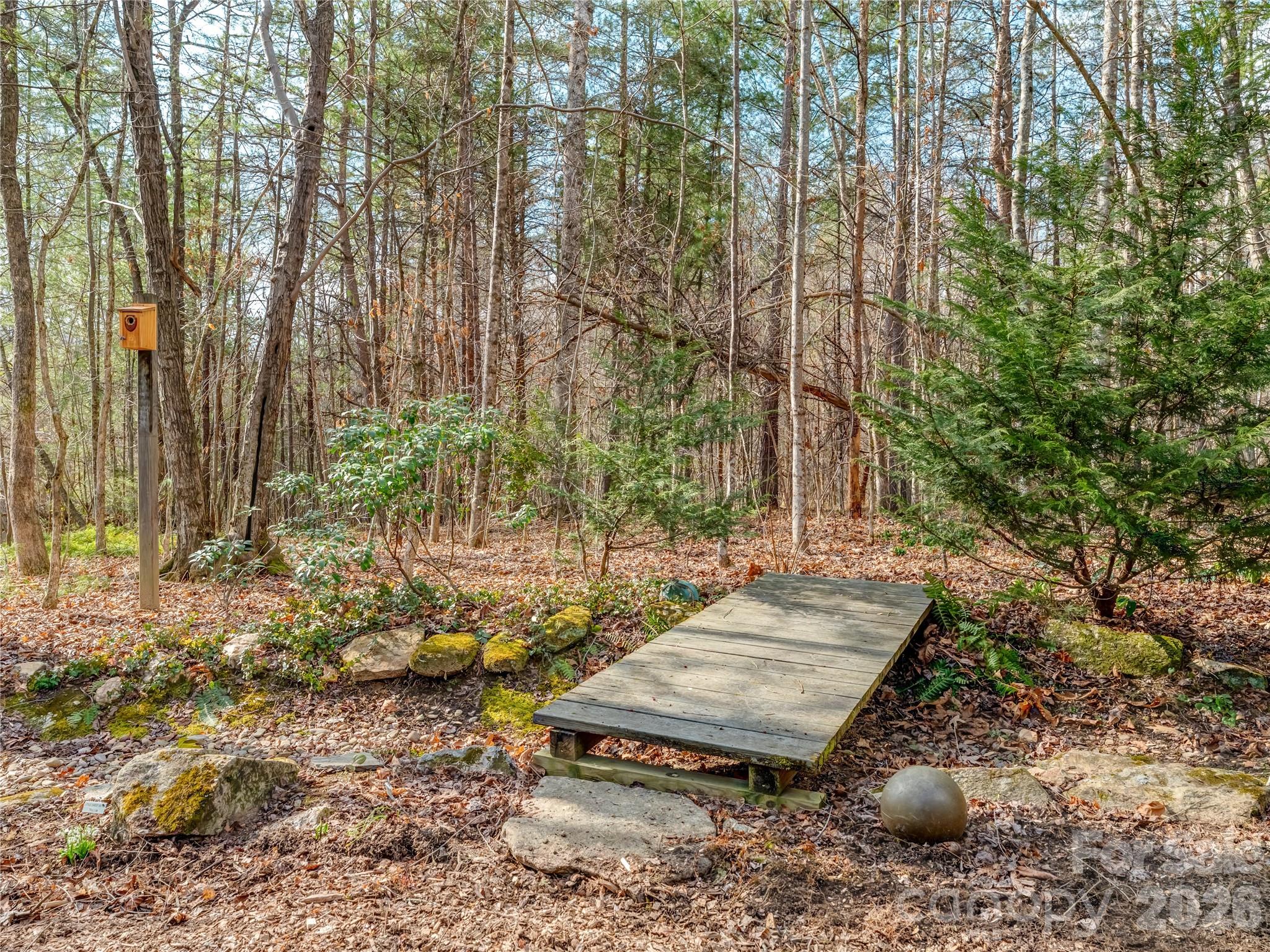 203 Heathcote Road Hendersonville, NC 28791 - Photo 39 of 47 a wooden bench sitting in the middle of a forest