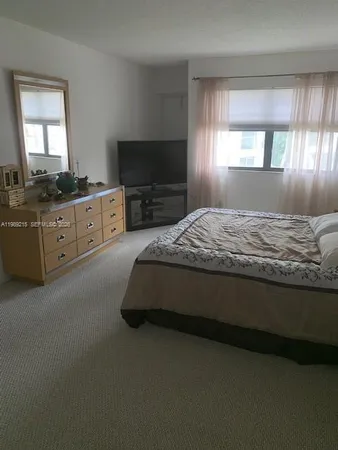 a spacious bedroom with a bed and a flat screen tv