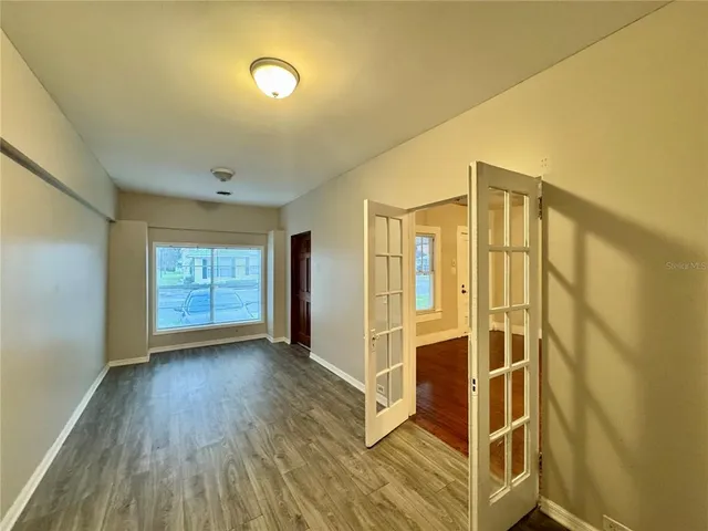 a view of an empty room with wooden floor and a window
