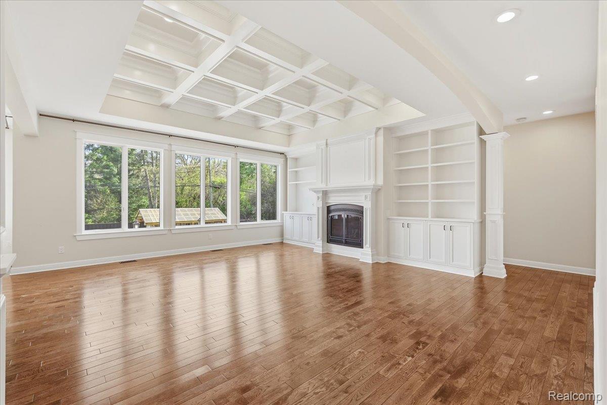 35339 West 13 Mile Road Farmington, MI 48331 - Photo 18 of 72 Great room featuring built in features, coffered ceiling, a glass covered fireplace, hardwood / wood-style flooring, and decorative columns