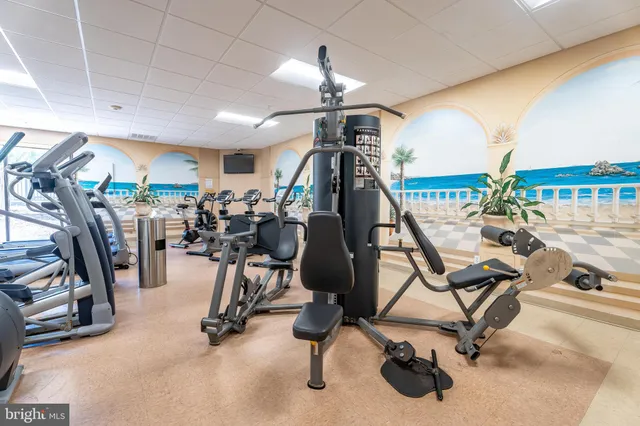 a room with lots of white furniture a chandelier and a flat screen tv