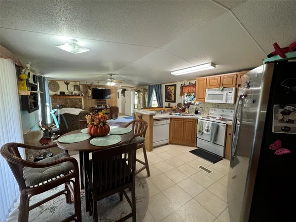 a kitchen with stainless steel appliances kitchen island granite countertop a table chairs and a refrigerator