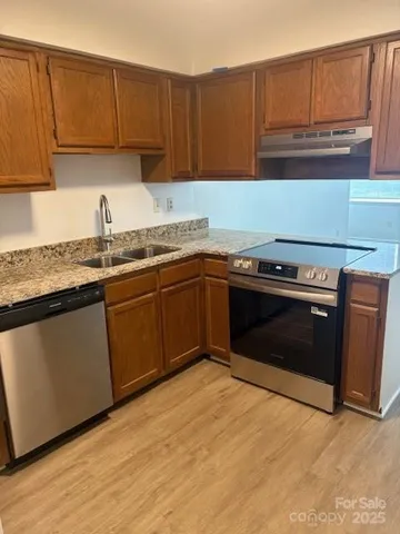 a kitchen with granite countertop a sink stove and cabinets