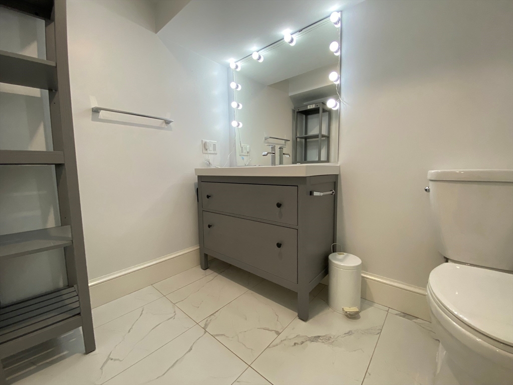 10 Gloucester Avenue, Unit B Gloucester, MA 01930 - Photo 11 of 13 a bathroom with a sink a toilet a mirror and vanity