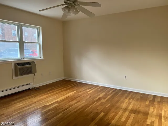 an empty room with wooden floor fan and windows
