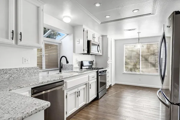 a kitchen with granite countertop a sink stove and cabinets