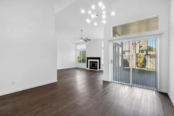 an empty room with wooden floor fireplace and chandelier