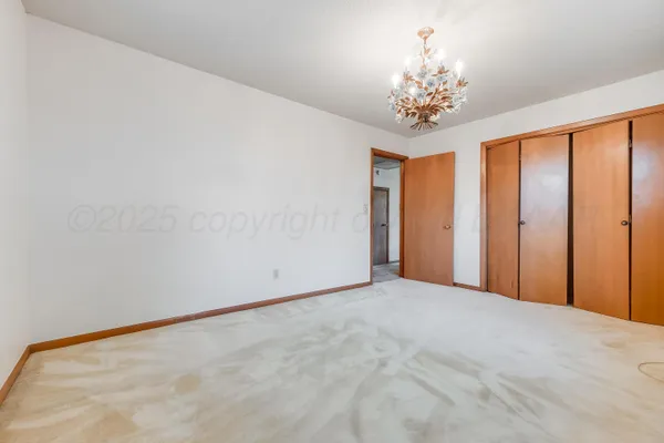 a view of an empty room with chandelier and a window