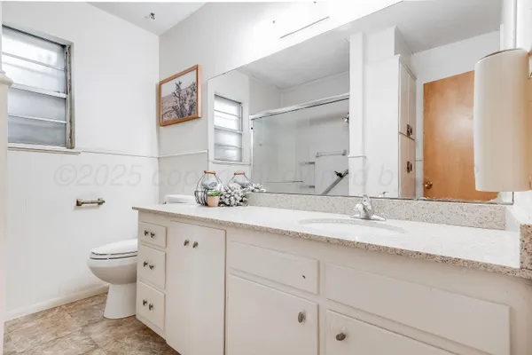 a bathroom with a granite countertop toilet sink and mirror