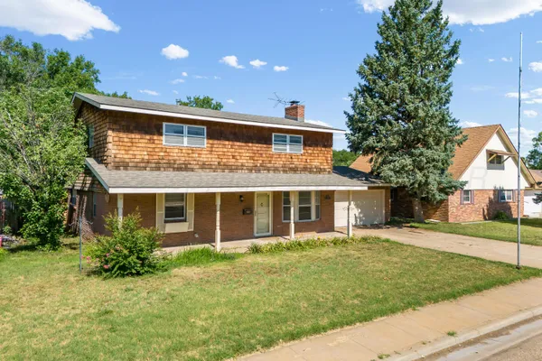 a front view of a house with a yard and potted plants