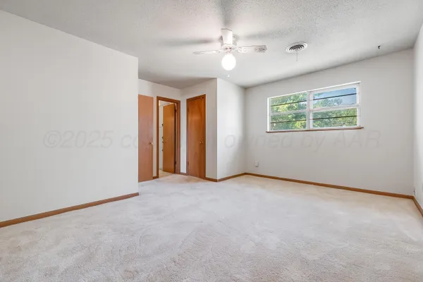 an empty room with chandelier fan and windows