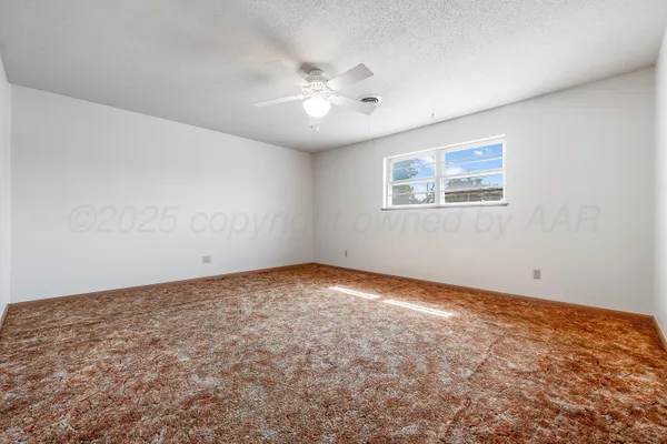 an empty room with a fan and a window
