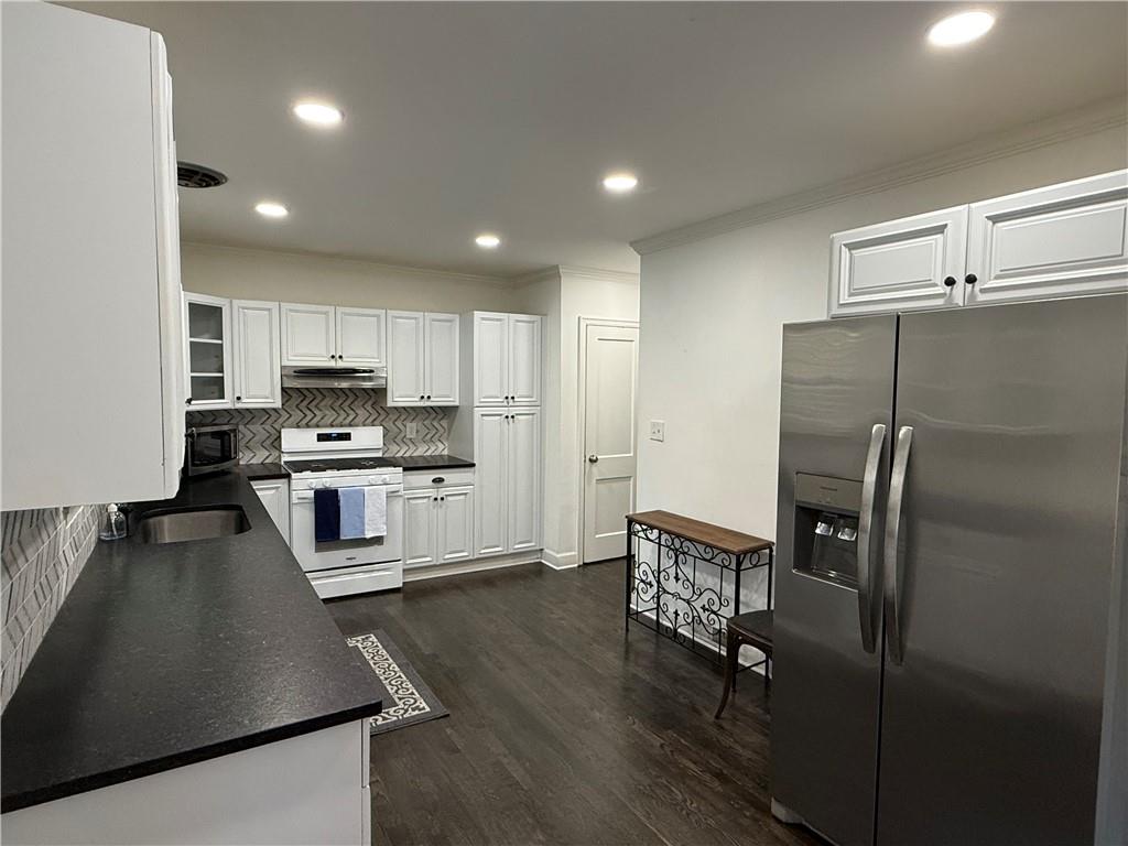 1140 Goodwin Place Northeast, Unit 4 Atlanta, GA 30319 - Photo 14 of 50 a kitchen with stainless steel appliances granite countertop a refrigerator a stove a sink a dining table and chairs