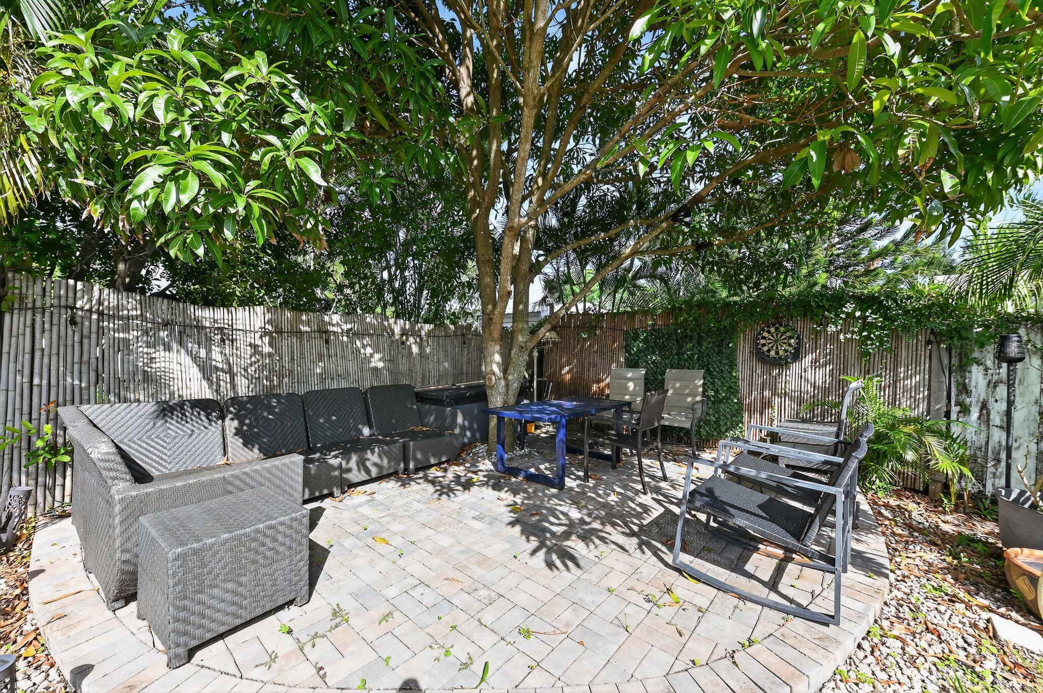 407 Highwood Circle Jupiter, FL 33458 - Photo 25 of 30 a view of a patio with table and chairs potted plants and large tree