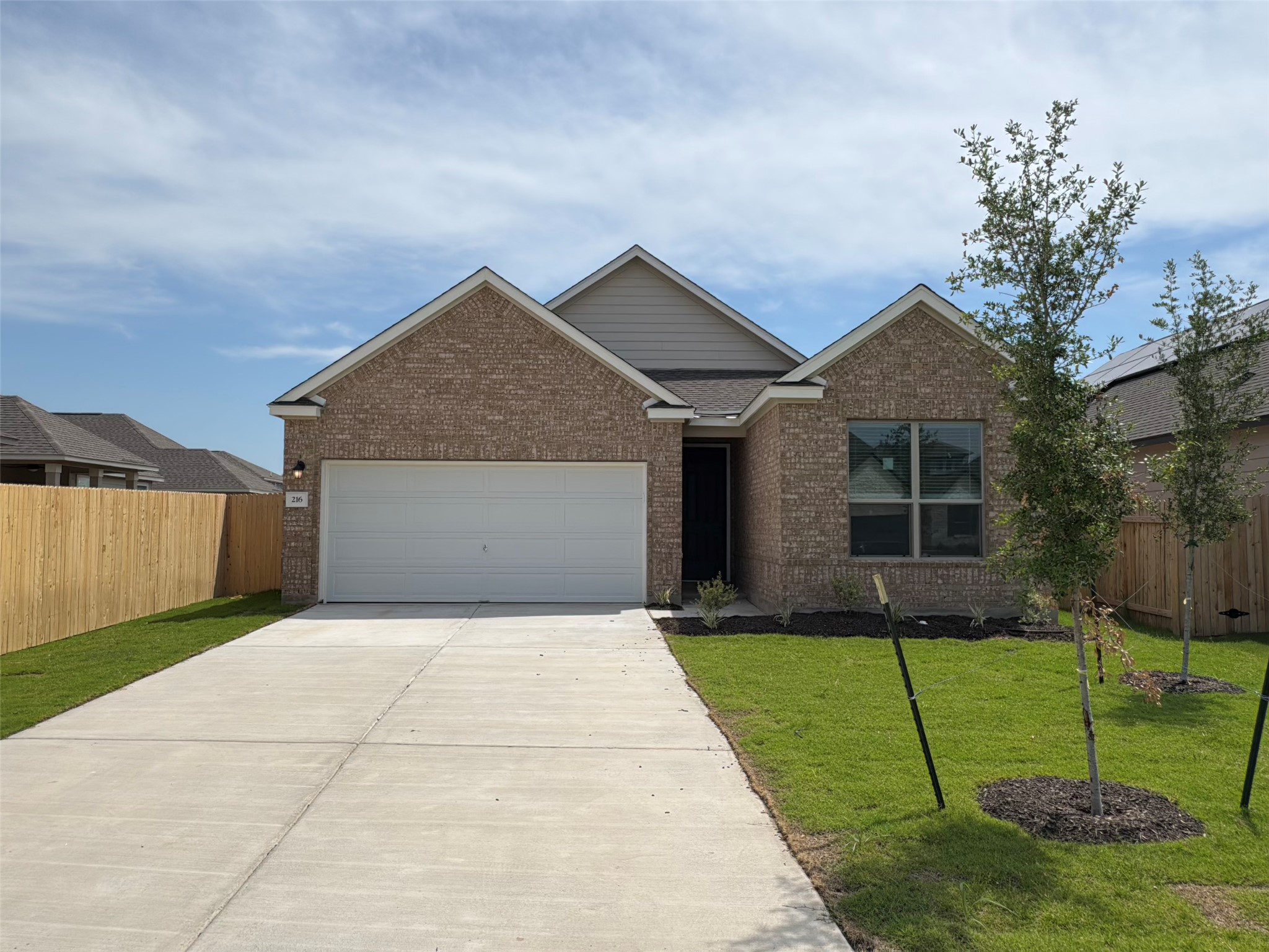 View of front of house with driveway, an attached garage, and brick siding