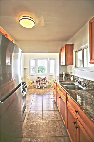 a large kitchen with stainless steel appliances granite countertop a stove a sink and a granite counter tops with a large window