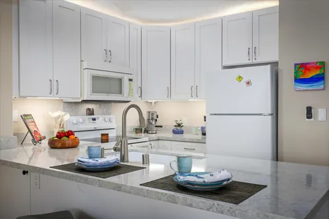 a kitchen with stainless steel appliances a sink a stove and white cabinets