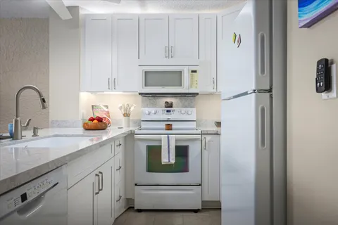 a kitchen with white cabinets and white appliances