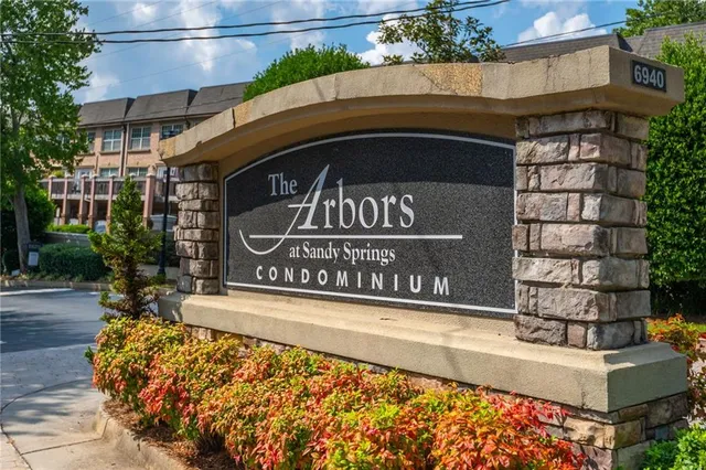 a view of sign board with buildings in the background