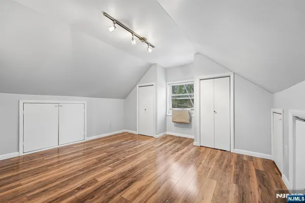 a big room with wooden floor closet and windows
