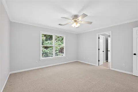 an empty room with chandelier fan and windows