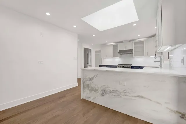 a large kitchen with stainless steel appliances a large counter top and a wooden floors