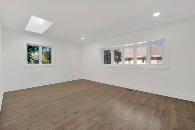 a view of empty room with wooden floor and window