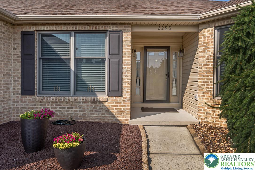 A welcoming brick exterior boasts a paved pathway leading to the entry, flanked by vibrant landscaping.