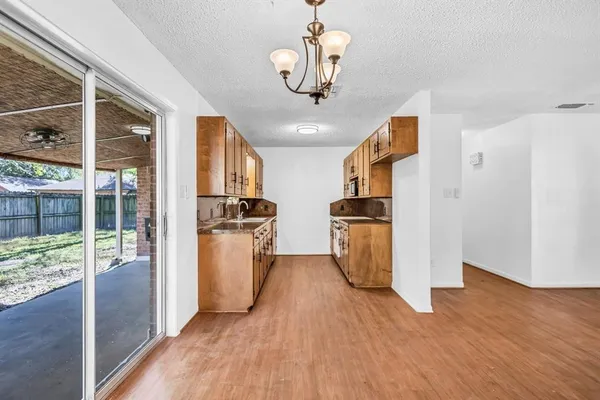 a kitchen with stainless steel appliances granite countertop a refrigerator a sink dishwasher a stove and a dining table with wooden floor