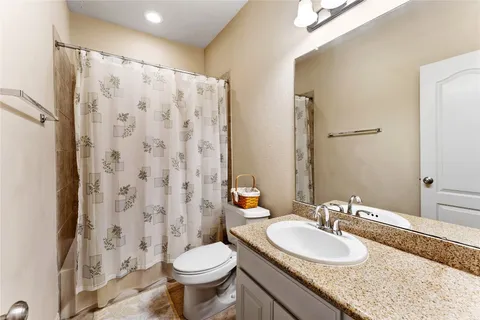a bathroom with a granite countertop sink toilet and a mirror