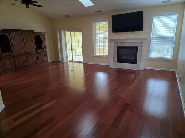 a view of a livingroom with wooden floor a fireplace and windows