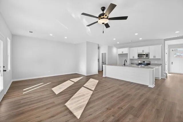 a view of kitchen and empty room with wooden floor