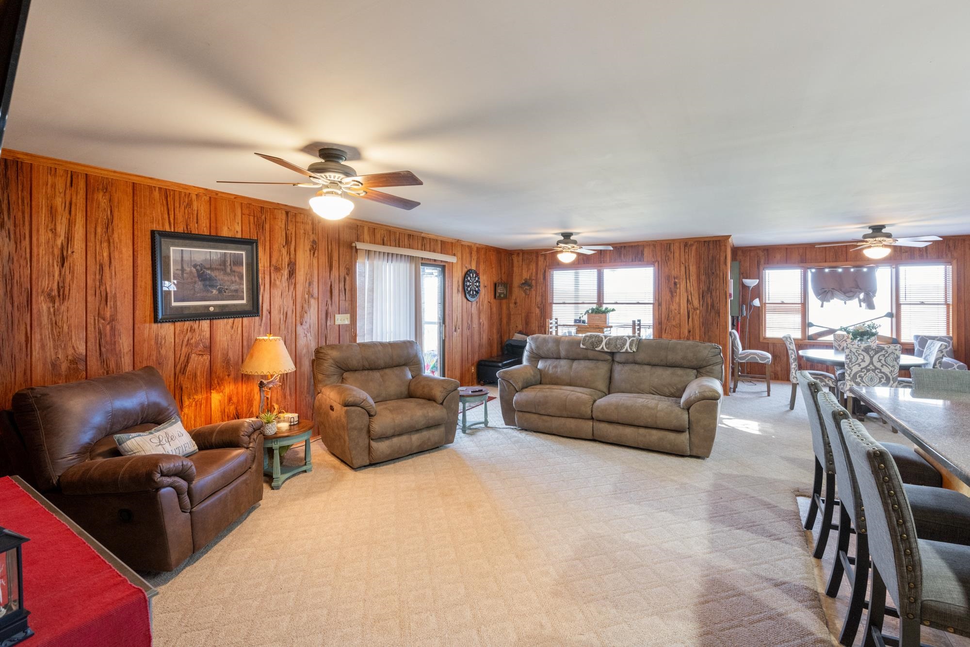Living area featuring a ceiling fan and wood walls