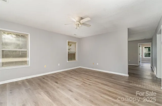 a view of an empty room with a window and wooden floor