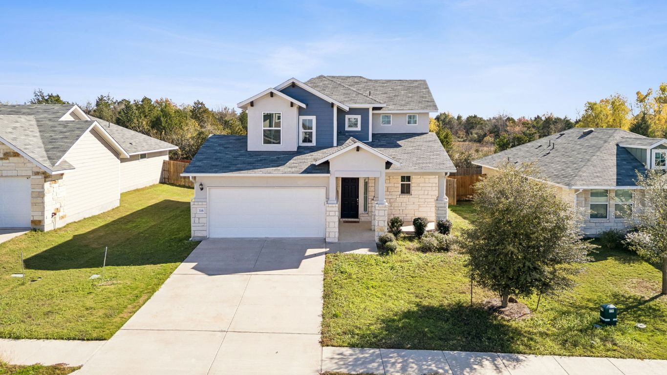 Traditional home with concrete driveway, a garage, and stone siding