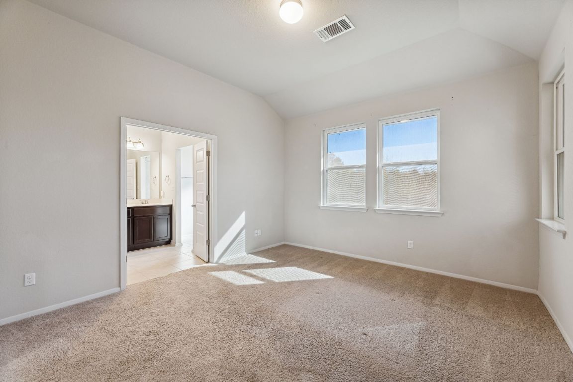 316 Insider Loop Elgin, TX 78621 - Photo 12 of 39 Unfurnished bedroom with vaulted ceiling, light colored carpet, and connected bathroom