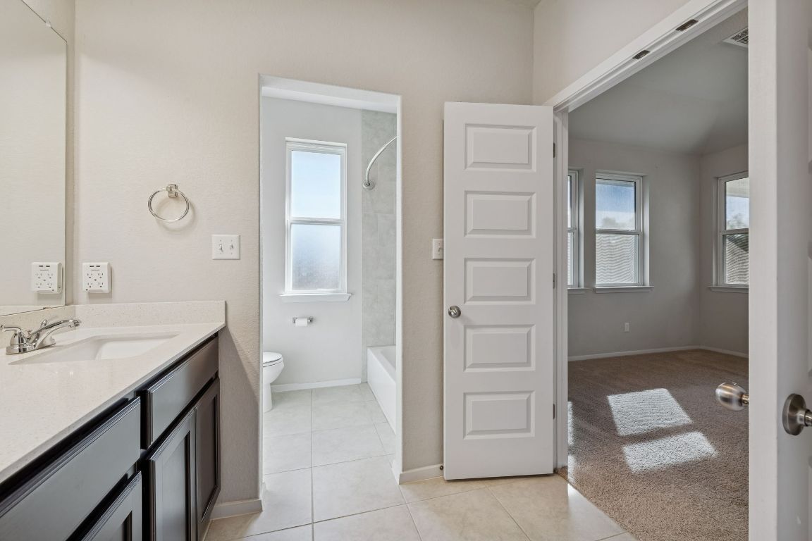 316 Insider Loop Elgin, TX 78621 - Photo 16 of 39 Bathroom with vanity, light tile patterned flooring, tub / shower combination, and light carpet