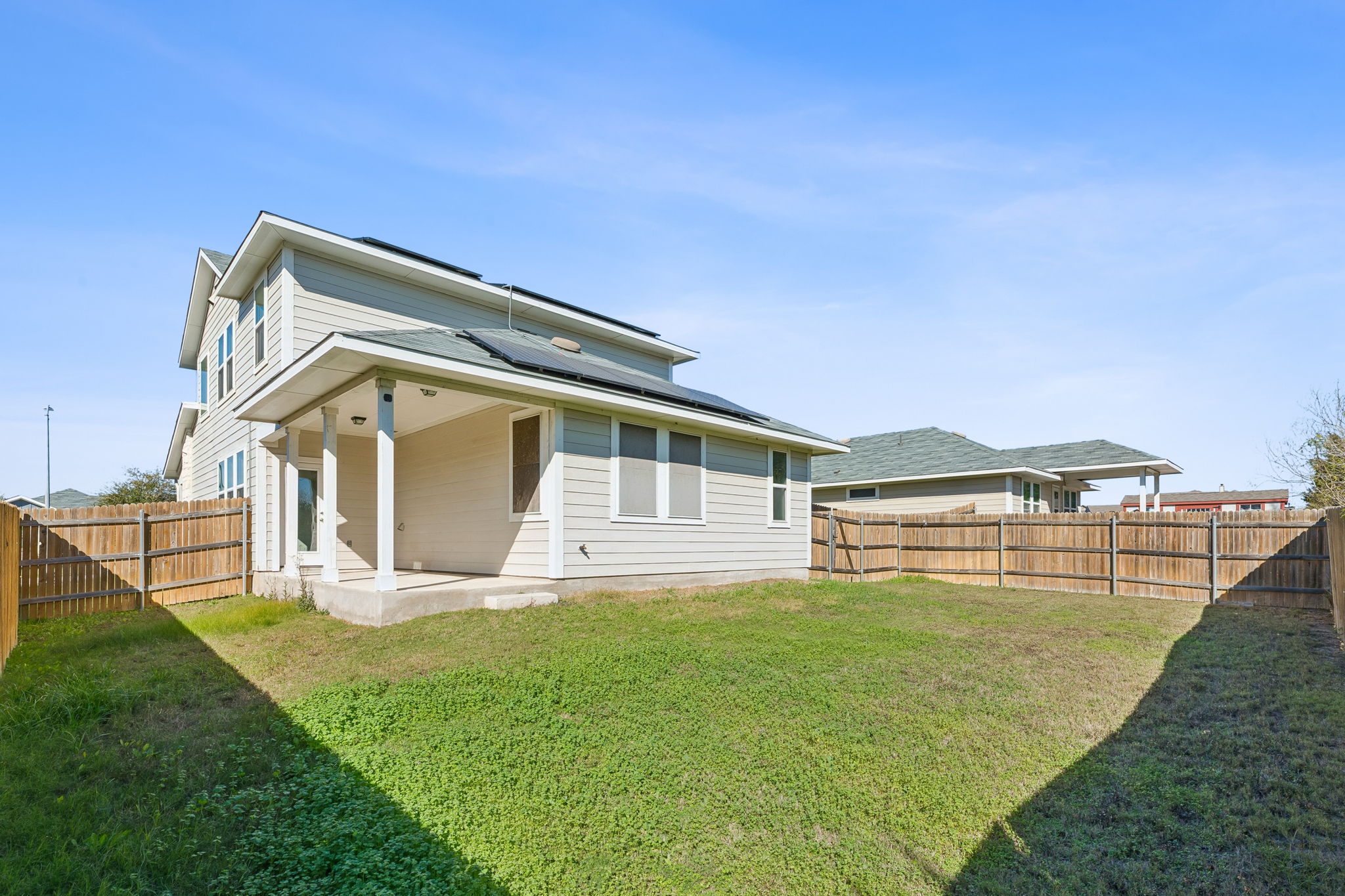 316 Insider Loop Elgin, TX 78621 - Photo 28 of 39 Rear view of house featuring a patio area, roof mounted solar panels, and a fenced backyard