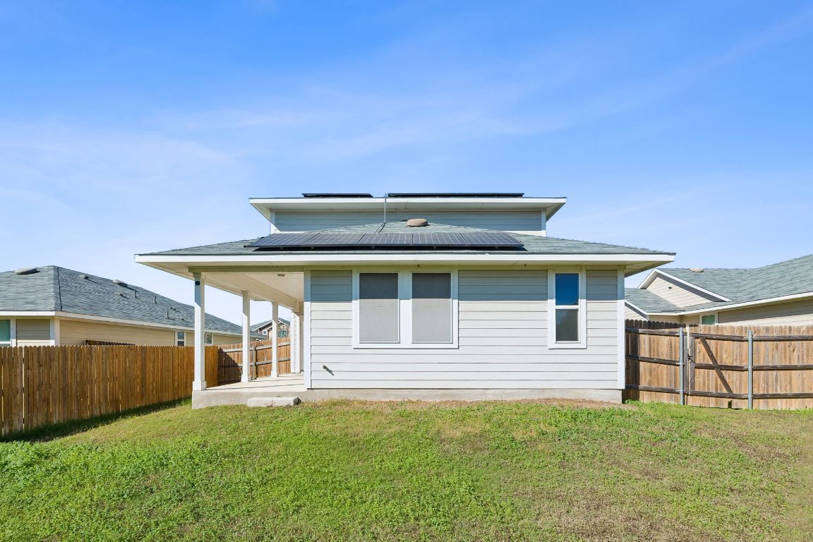 316 Insider Loop Elgin, TX 78621 - Photo 30 of 39 Rear view of house with roof mounted solar panels, a patio, and a fenced backyard