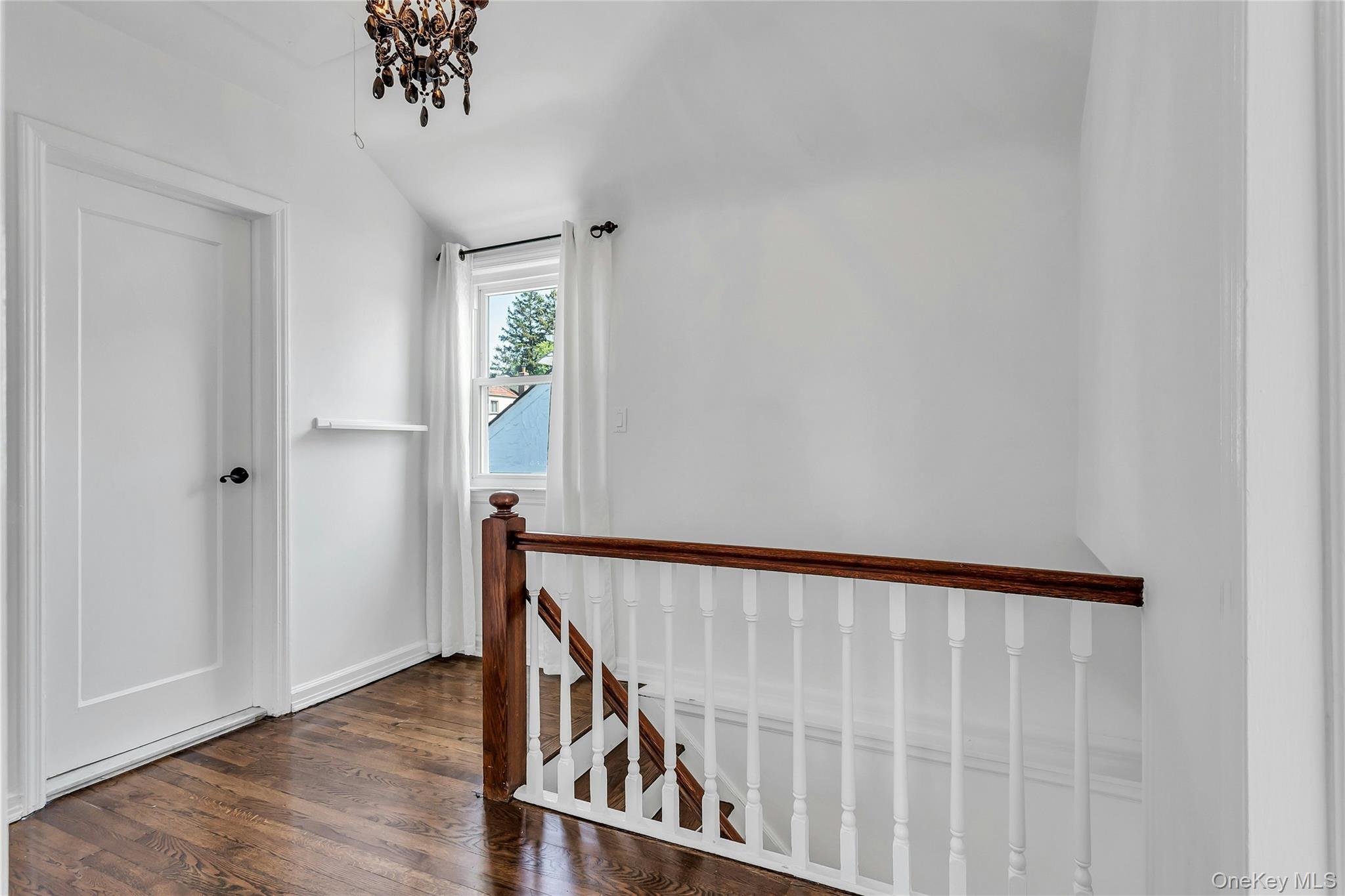79-31 211th Street Queens, NY 11364 - Photo 11 of 28 Stairway featuring wood finished floors, a chandelier, and baseboards