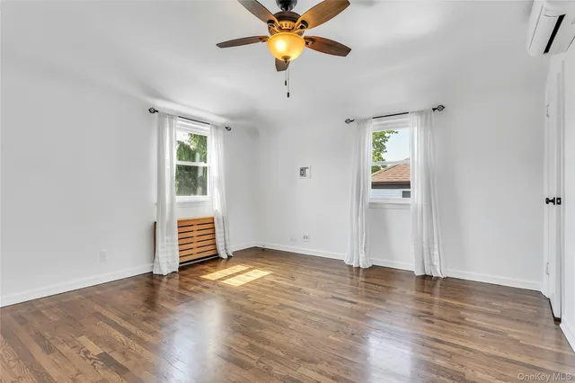 an empty room with wooden floor chandelier fan and windows