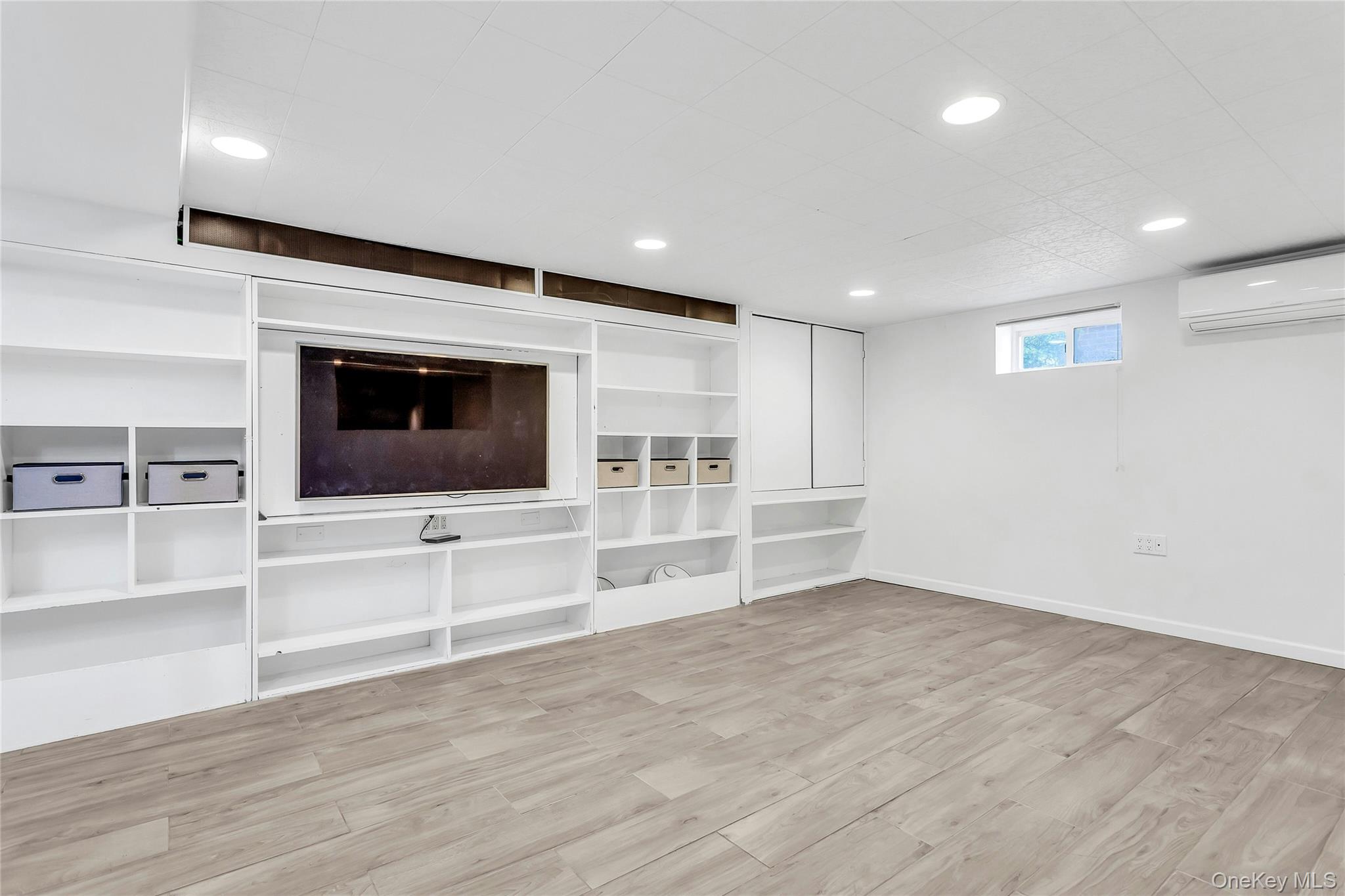 79-31 211th Street Queens, NY 11364 - Photo 19 of 28 Basement family room with a ductless AC, wood finished floors, recessed lighting, and baseboards