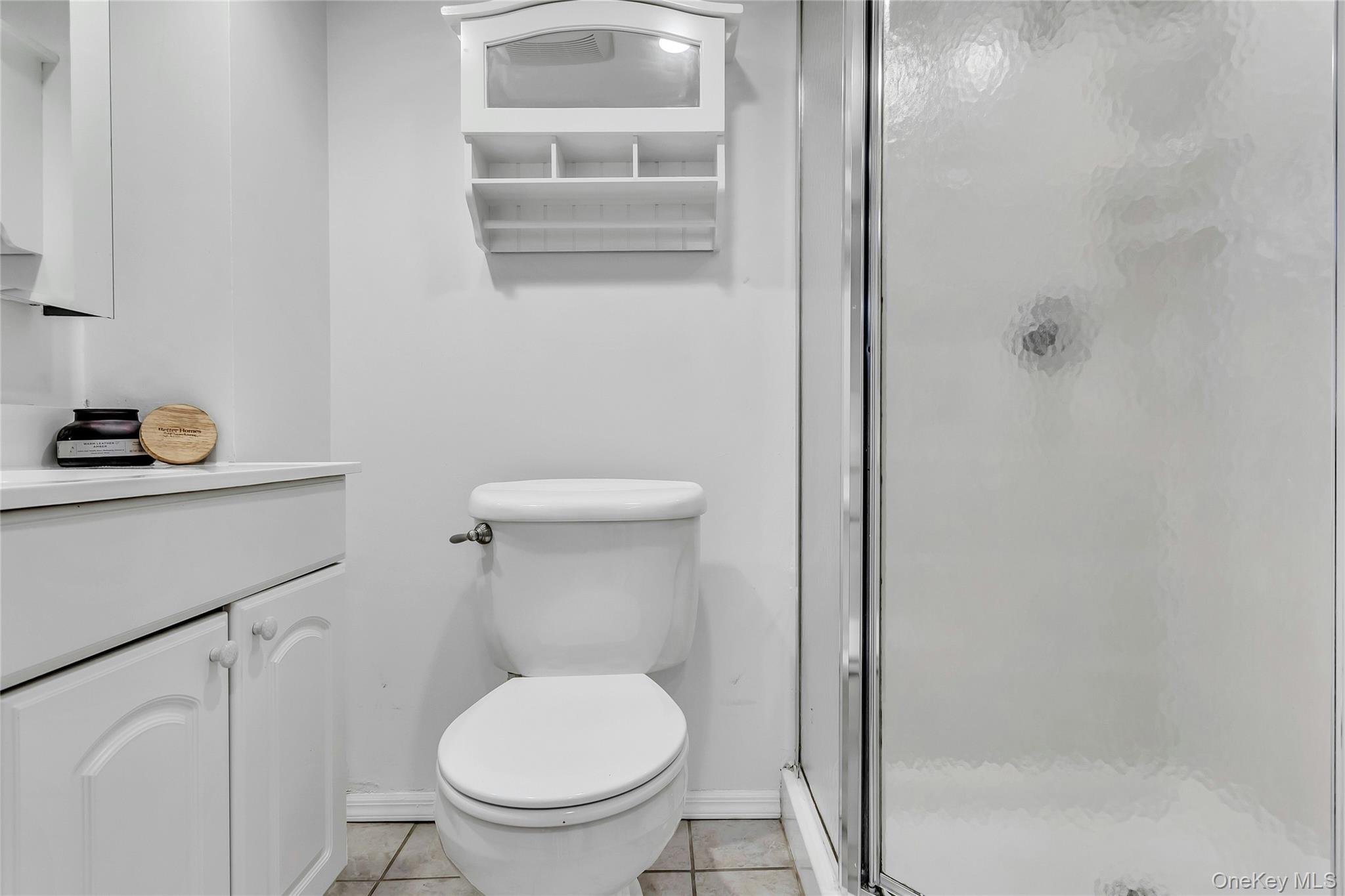 79-31 211th Street Queens, NY 11364 - Photo 23 of 28 Bathroom featuring a shower stall, tile patterned flooring, toilet, vanity, and baseboards